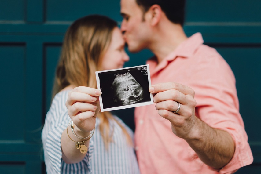 Paar hält Ultraschallbild vom Baby in die Kamera